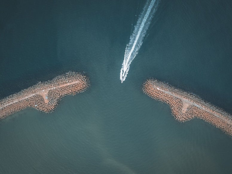 An Aerial Shot of a Boat going through an Inlet, photo by Pok Rie / Pexels