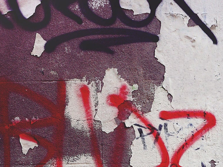 A wall with paint pealing off and graffiti tags. Credits: Pexels / Suzy Hazelwood