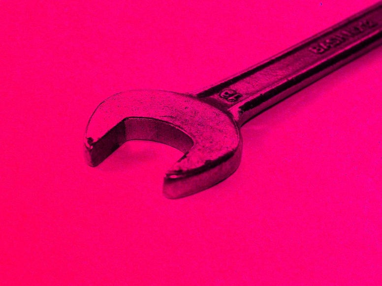 A wrench on a pink background